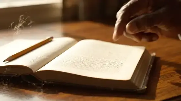 A man's finger running down a column of small print in a thick open reference book and stopping on one line